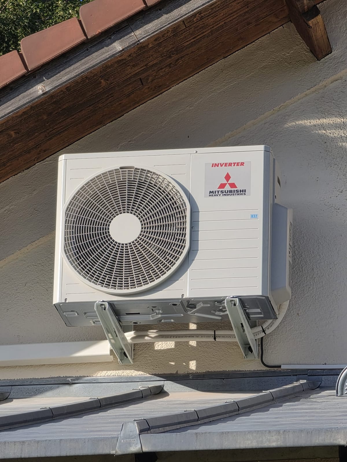 Groupe extérieur Mitsubishi — Unité extérieure posée sur équerres, sous débord de toiture.